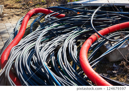 A variety of coiled electrical cables in multiple colors are spread out on the ground surface A variety of coiled electrical cables in multiple colors are spread out on the ground surface 124679397
