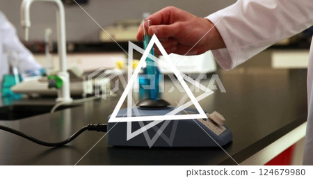 Hand holding test tube over laboratory equipment with triangle image Hand holding test tube over laboratory equipment with triangle image 124679980