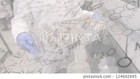 Chemical formulas image over scientist handling test tubes in laboratory 124682695