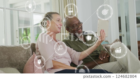 Icons representing education and technology image over couple using tablet on couch 124682804
