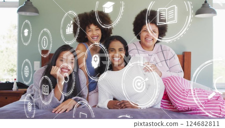 Icons representing technology and education image over diverse women relaxing on bed 124682811
