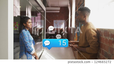 Image of media icons over diverse colleagues discussing work in office 124683272