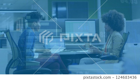 Image of diagrams and data processing over biracial female colleagues talking in office 124683436