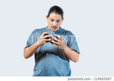 Surprised young man playing with cell phone isolated. Amazed gamer playing with cell phone isolated Surprised young man playing with cell phone isolated. Amazed gamer playing with cell phone isolated 124685097