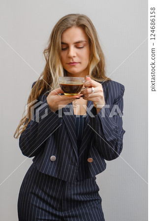 Woman in a striped suit enjoying coffee in a minimalist setting at a modern hour 124686158