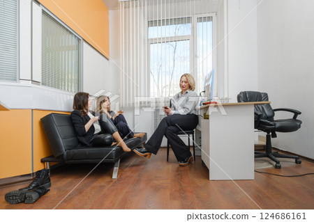 Women engaged in discussion in a modern office setting during daytime Women engaged in discussion in a modern office setting during daytime 124686161