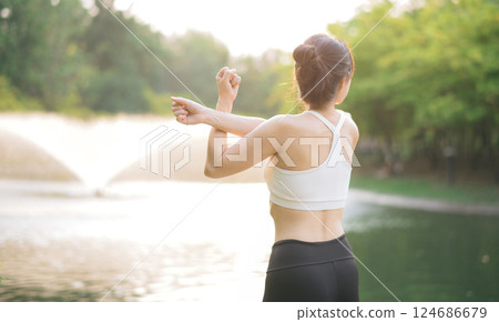 Female jogger. Fit young Asian woman with sportswear stretching muscle in park before running and enjoying healthy outdoor. Fitness runner girl in public park. Wellness being concept 124686679