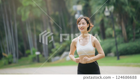 asian woman jogger running in green nature public park. 124686688