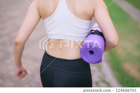 back of fitness yoga woman walking in the park with yoga mat 124686701