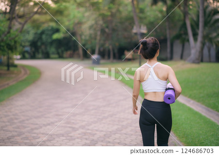 back of fitness yoga woman walking in the park with yoga mat 124686703