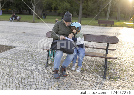 Grandfather and grandson drawing together in park Grandfather and grandson drawing together in park 124687256