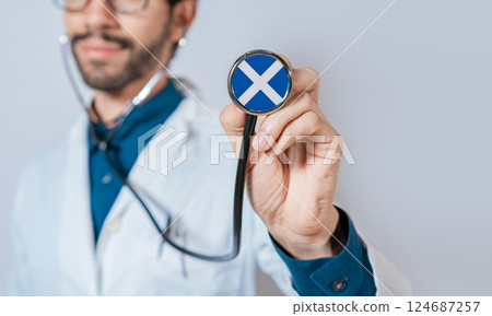 Doctor holding stethoscope with Scotland flag. Scotland health and care concept, Scotland flag on stethoscope Doctor holding stethoscope with Scotland flag. Scotland health and care concept, Scotland flag on stethoscope 124687257