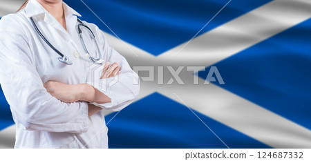 Doctor with crossed arms on Scottish flag. Scotland health and care concept. Female doctor on Scottish flag 124687332