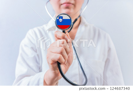 Female doctor holding stethoscope with Slovenia flag. National health system of Slovenia 124687340