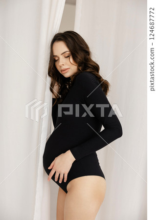 Pregnant Model Posing in Black Bodysuit Holding White Curtain Pregnant Model Posing in Black Bodysuit Holding White Curtain 124687772
