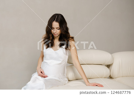 Pregnant Model Posing on White Sofa in Studio Pregnant Model Posing on White Sofa in Studio 124687776