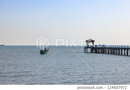 Small fishing boat near Pier at the sea, jetty and sea in sun light. Small fishing boat near Pier at the sea, jetty and sea in sun light. 124687972