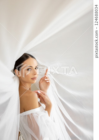 Bride holding veil looking away in wedding dress Bride holding veil looking away in wedding dress 124688034