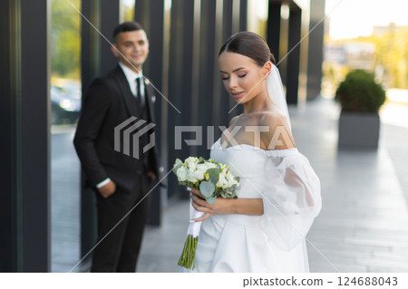 Elegant bride and groom posing near modern building on wedding day 124688043