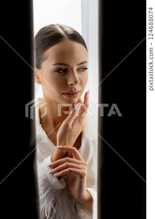 Bride hiding behind curtains looking down with closed eyes and hands near her face 124688074