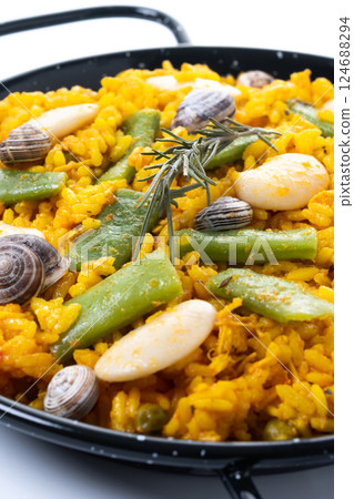 Traditional Valencian paella with rabbit, chicken, garrofon beans, snails, Moroccan green beans and saffron on black background. 124688294