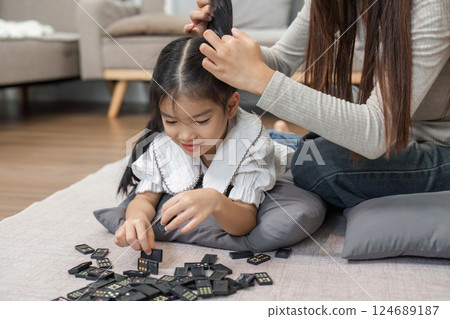 Creative Play and Hair Styling. A loving mother teaches her daughter how to style her hair while playing with dominoes. Creative Play and Hair Styling. A loving mother teaches her daughter how to style her hair while playing with dominoes. 124689187