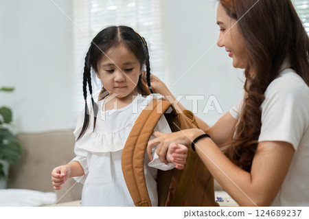 Back to School and Family Bonding. A young girl prepares for school with her mother, sharing a moment of love and support. 124689237