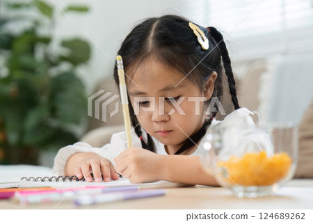 Back to School and Learning Fun. A focused girl studying on a notebook at home, practicing her writing skills. Back to School and Learning Fun. A focused girl studying on a notebook at home, practicing her writing skills. 124689262