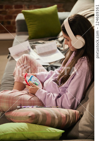 Girl stitching embroidery hoop with concentration, practicing hands-on activity during remote learning at home in comfy outfit. Girl stitching embroidery hoop with concentration, practicing hands-on activity during remote learning at home in comfy outfit. 124689361