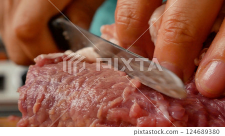 A woman slices pork meat. Cooking meat dishes. A woman slices pork meat. Cooking meat dishes. 124689380