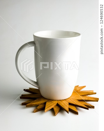 White cup on wooden hot stand in snowflake shape isolated on white background. White cup on wooden hot stand in snowflake shape isolated on white background. 124690532