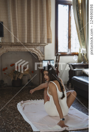 An elegant woman sits comfortably indoors, bathed in soft, natural light for a warm ambiance An elegant woman sits comfortably indoors, bathed in soft, natural light for a warm ambiance 124690898