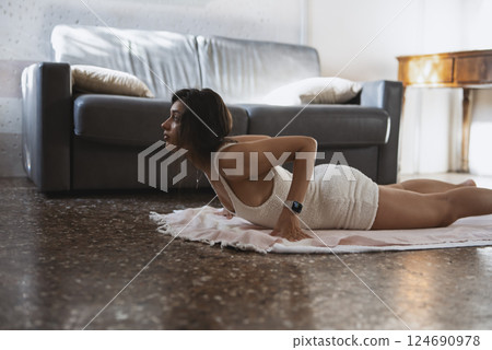 A woman is practicing a yoga pose in her stylish and beautifully decorated living room 124690978