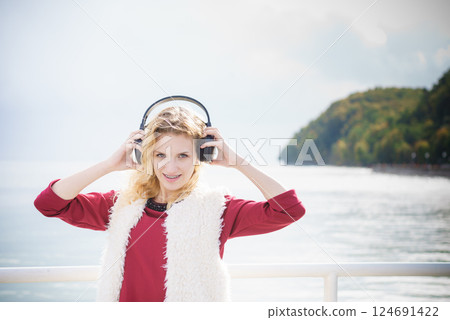 Happy woman wearing headphones outdoor 124691422