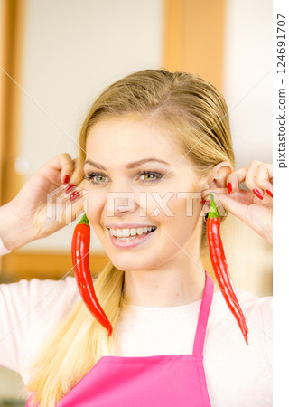Woman holding two chilli peppers Woman holding two chilli peppers 124691707