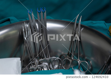 Surgical clamps and forceps in stainless steel bowl on medical drape, prepared for medical procedure 124692410