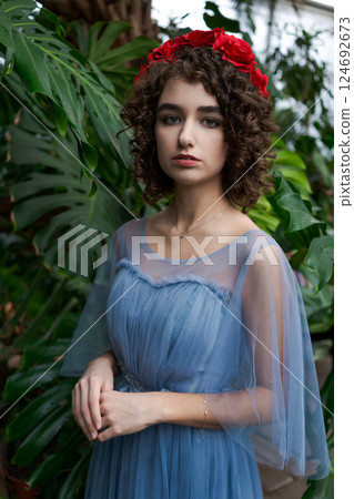 Woman wearing a blue dress and a red flower headband 124692673