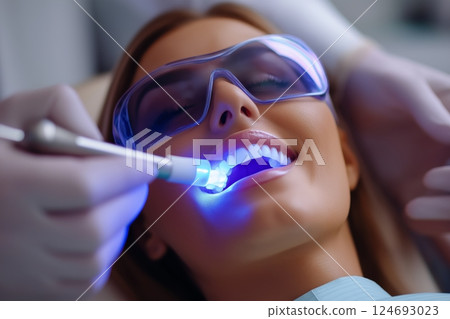 Woman receiving dental treatment in reclining chair with blue light 124693023