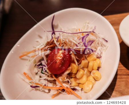close up of cherry tomato, sweet corns, shredded cabbage, purple cabbage, shredded carrots, and served in white bowl  124693428