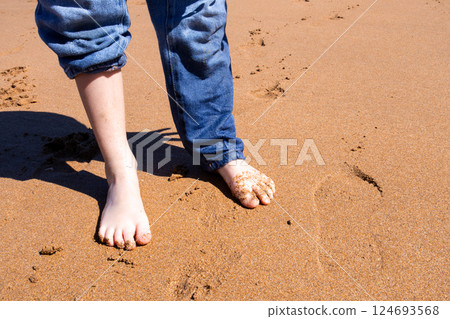Child feet on sandy beach with rolled up jeans on a sunny day 124693568