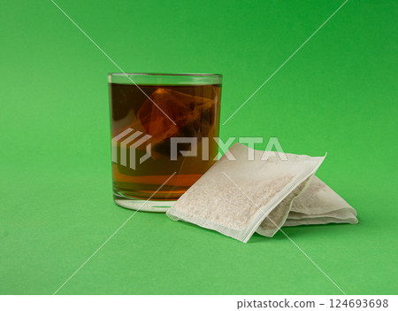 Herbal tea sachet in glass, hot water with chamomile and Hypericum or St. John's wort teabag 124693698