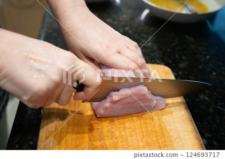 Raw turkey fillet slicing for nuggets or escalope, cut meat with kitchen knife, homemade schnitzel Raw turkey fillet slicing for nuggets or escalope, cut meat with kitchen knife, homemade schnitzel 124693717