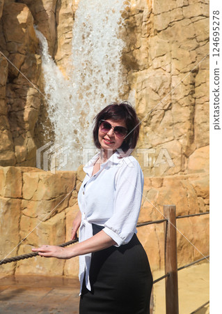 A female tourist near an artificial waterfall in a resort town A female tourist near an artificial waterfall in a resort town 124695278