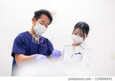 進行牙科治療的牙醫和牙科助理 進行牙科治療的牙醫和牙科助理 124696041