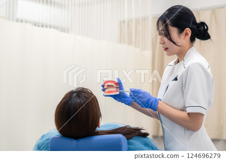 一名女牙科助理使用牙齒模型向患者解釋 124696279