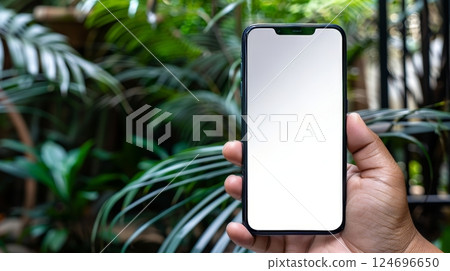 Hand holding smartphone with blank screen in sunny outdoor setting on a beautiful day 124696650