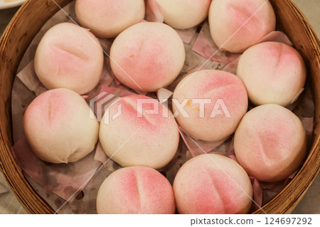 close up of steamed many Chinese steamed Birthday Peach Buns (longevity bun) stuffed with sweetened lotus seed paste in a bamboo steamer for celebrating birthday 124697292