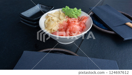 Pickled ginger and wasabi bowl on dark table, traditional Japanese condiments served with sushi Pickled ginger and wasabi bowl on dark table, traditional Japanese condiments served with sushi 124697612