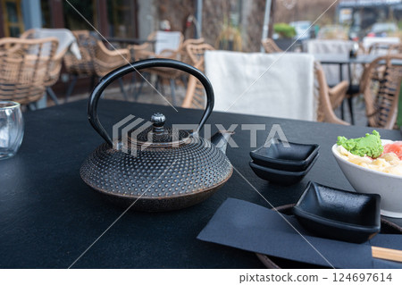 Japanese tea pot, black metal teapot, traditional iron kettle for tea drinking while waiting for sushi Japanese tea pot, black metal teapot, traditional iron kettle for tea drinking while waiting for sushi 124697614