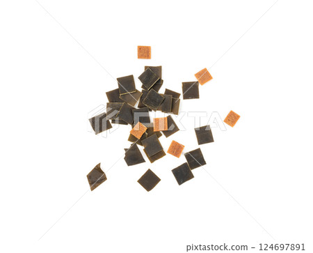 Dry kelp seaweed squares, mini wakame pieces isolated, dried kombu and carrot flakes from ramen Dry kelp seaweed squares, mini wakame pieces isolated, dried kombu and carrot flakes from ramen 124697891